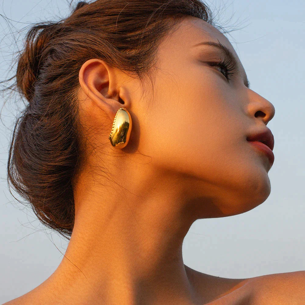 The Féerique Earrings displayed in silver and gold, emphasizing their timeless style and luxury.
